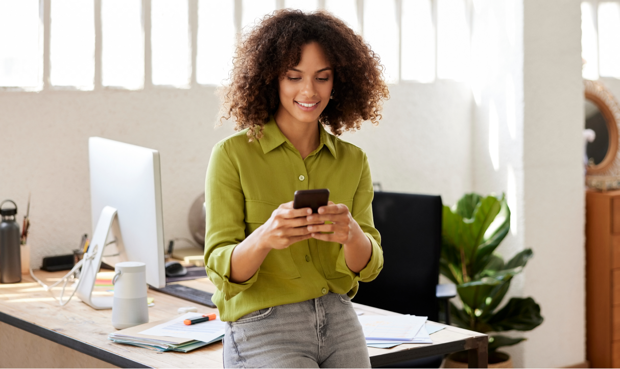 A woman smiles as she looks at the phone in her hands