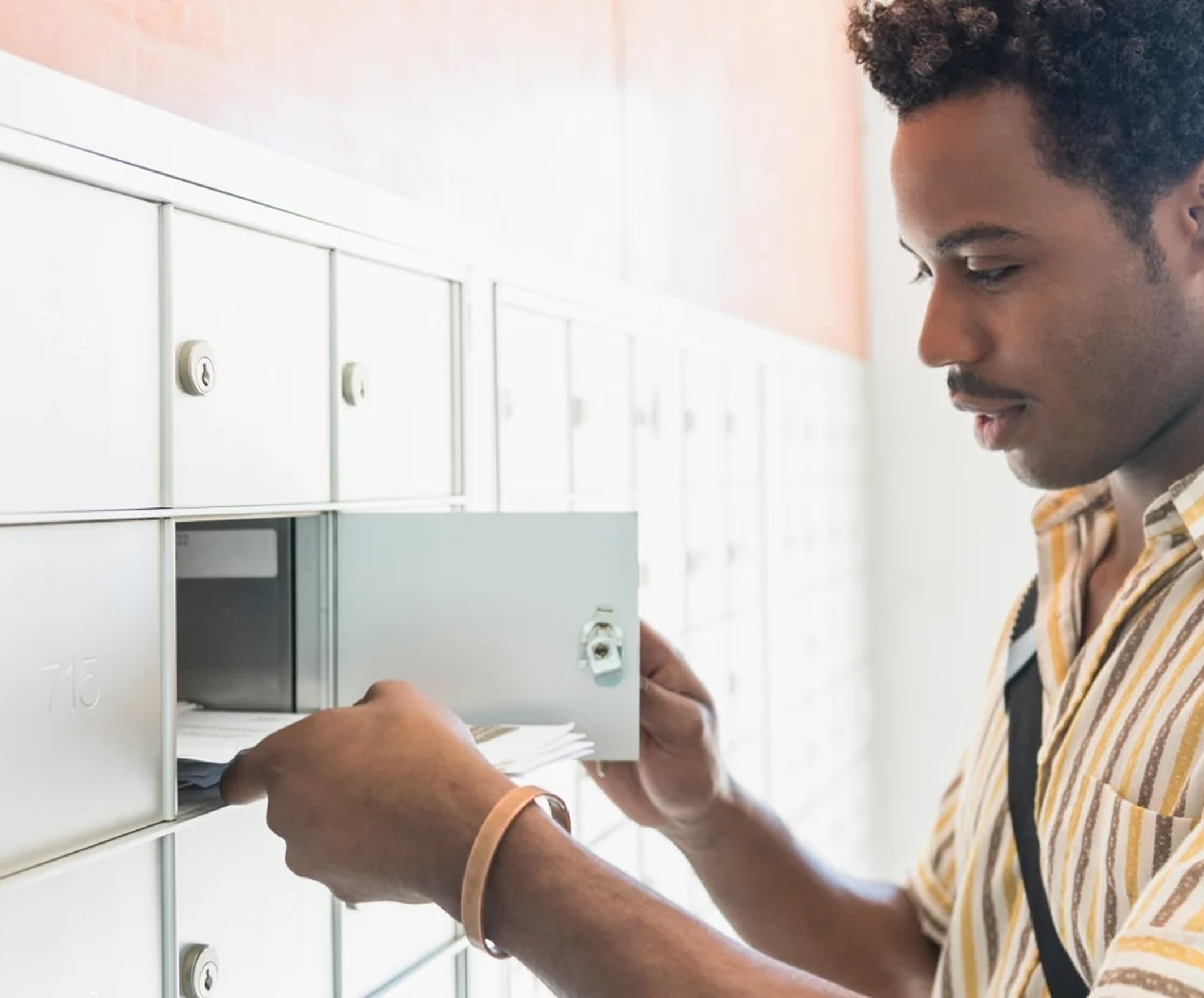 Man retrieving mail from a cluster mailbox unit.