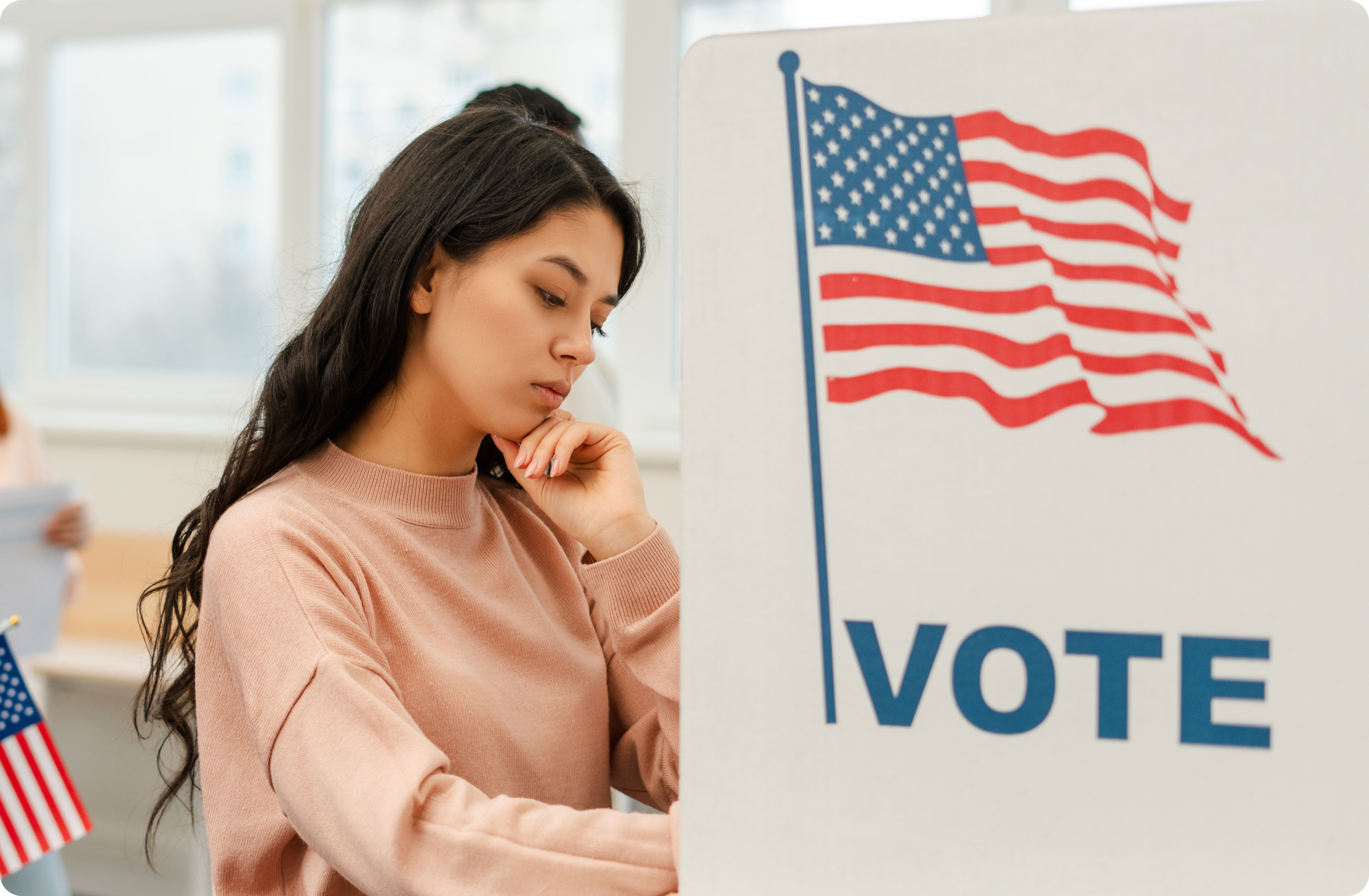 Woman at a voting booth with a flag on the privacy panel.