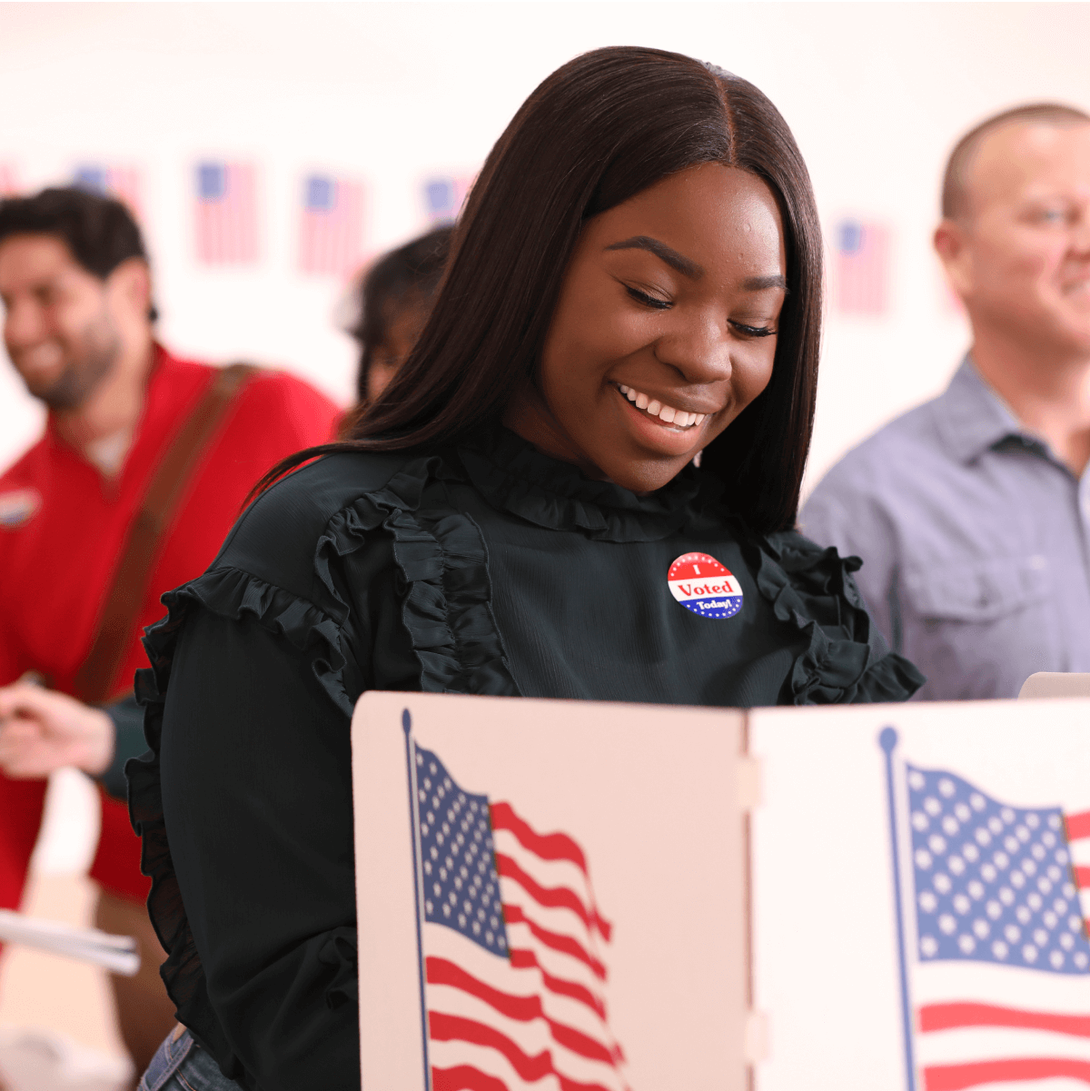 Woman smiling while casting a vote in a booth.